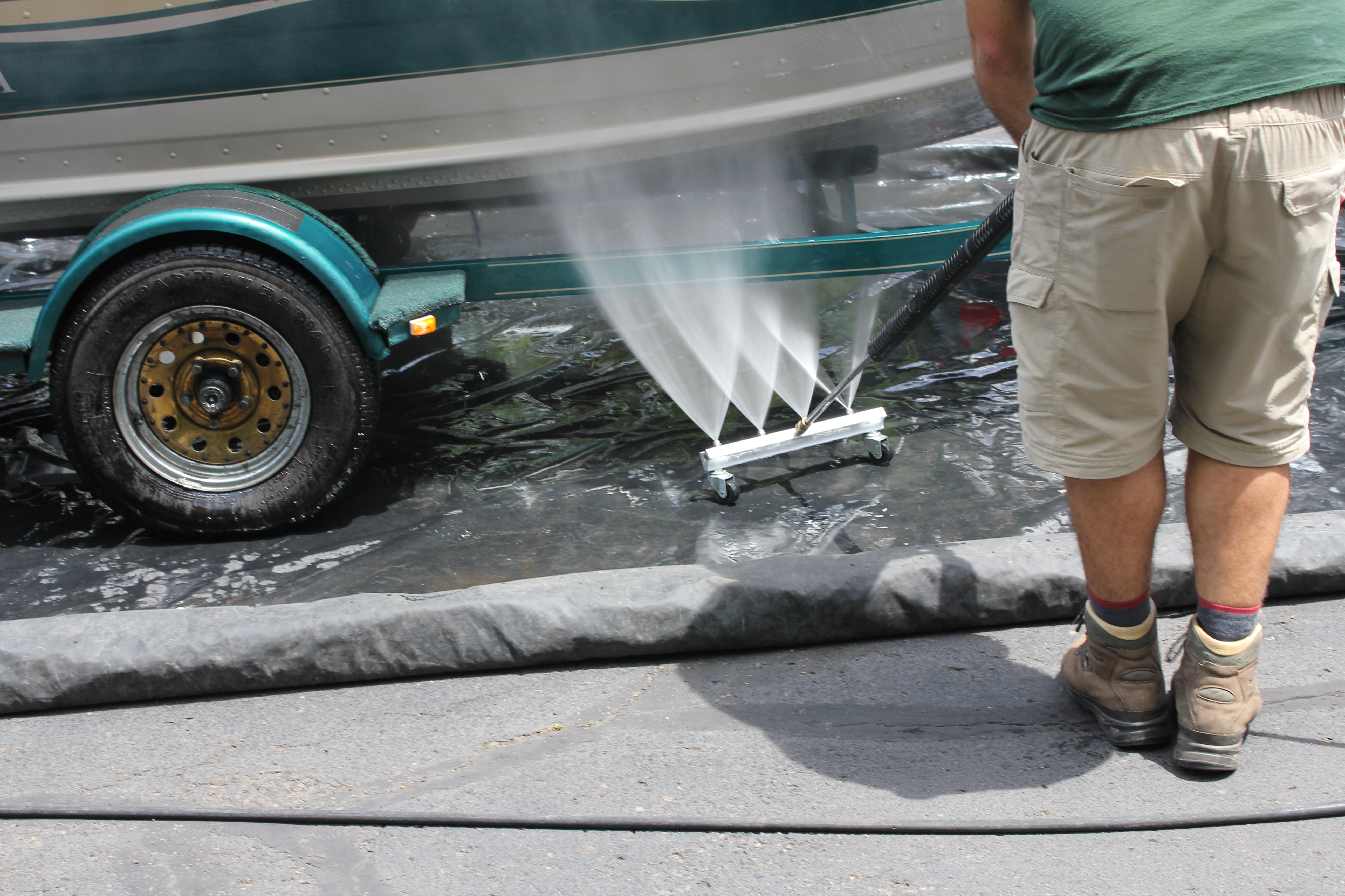 Underboat spray boat cleaning system operated by man.